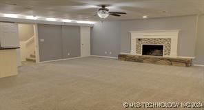 unfurnished living room featuring light carpet, a fireplace, and ceiling fan