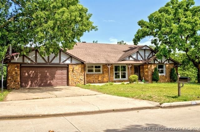 tudor-style house with a front yard and a garage