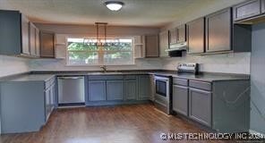 kitchen with sink, dark wood-type flooring, hanging light fixtures, and stainless steel appliances