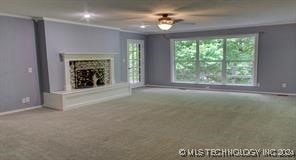 unfurnished living room with carpet flooring, ornamental molding, and ceiling fan