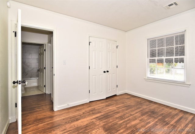 unfurnished bedroom featuring crown molding, a closet, and dark wood-type flooring