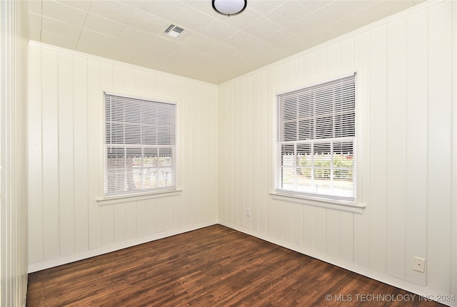 empty room featuring wood walls and dark hardwood / wood-style flooring