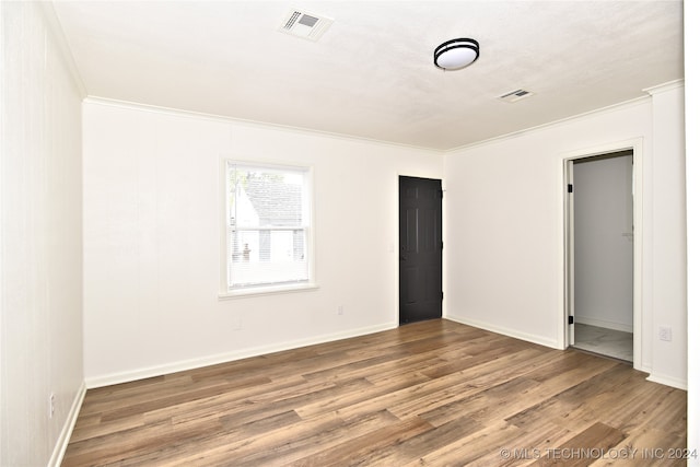 empty room with crown molding and wood-type flooring