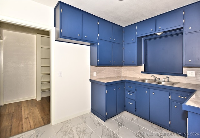 kitchen with blue cabinetry, decorative backsplash, and sink