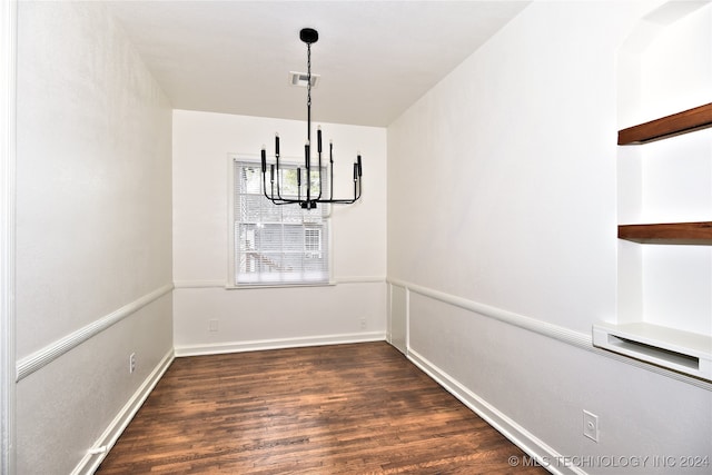 unfurnished dining area featuring a notable chandelier and dark hardwood / wood-style floors