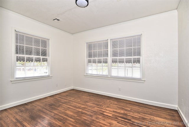 empty room featuring a wealth of natural light, ornamental molding, and dark hardwood / wood-style floors