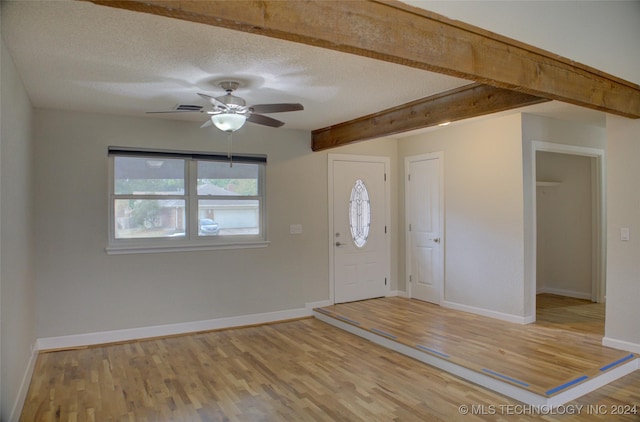 foyer entrance featuring ceiling fan, beam ceiling, wood-type flooring, and a textured ceiling