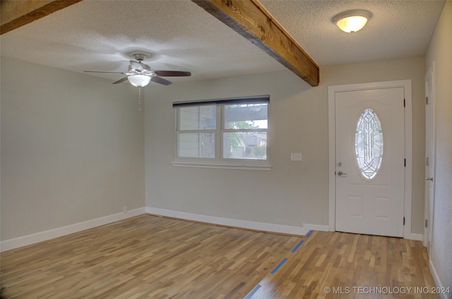 foyer with ceiling fan, beam ceiling, light hardwood / wood-style floors, and a textured ceiling