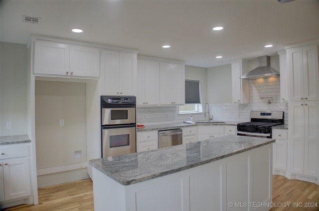 kitchen with sink, stainless steel appliances, white cabinets, and wall chimney exhaust hood