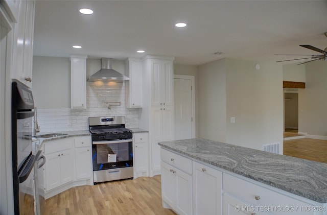 kitchen with white cabinetry, light stone counters, gas stove, light wood-type flooring, and wall chimney exhaust hood