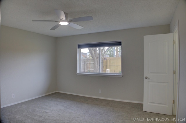 carpeted empty room featuring ceiling fan and a textured ceiling