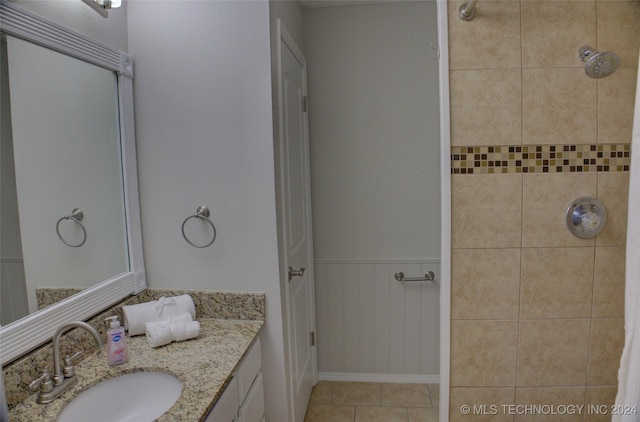 bathroom featuring tile patterned flooring, vanity, and a tile shower