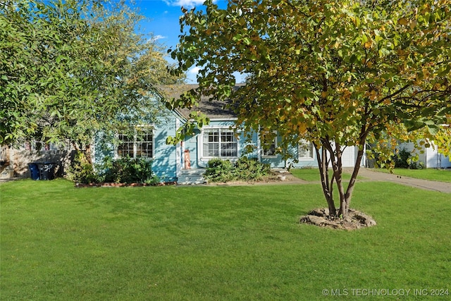 view of property hidden behind natural elements with a front yard and a garage