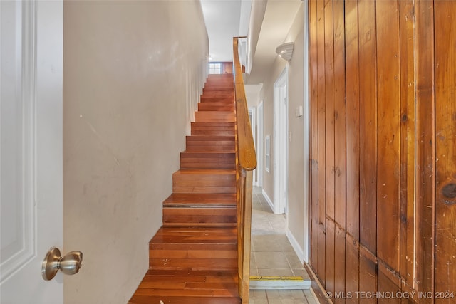 stairway with wooden walls and tile patterned flooring