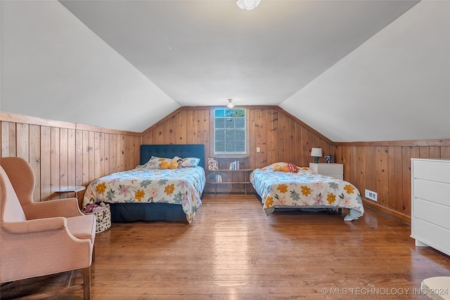 bedroom with hardwood / wood-style flooring, vaulted ceiling, and wooden walls