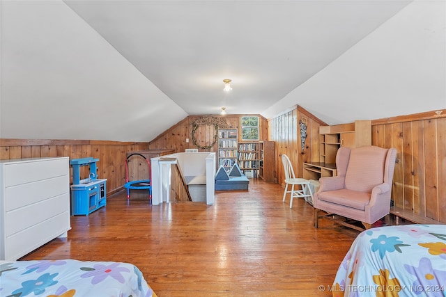 bedroom featuring wood walls, lofted ceiling, and light wood-type flooring