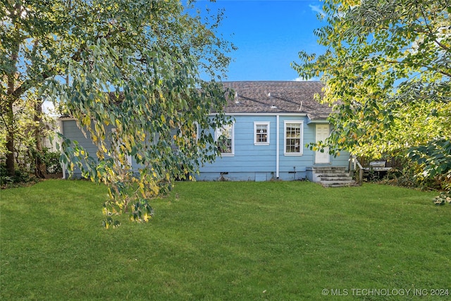 rear view of property featuring a lawn