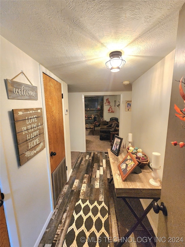 corridor with dark wood-type flooring and a textured ceiling