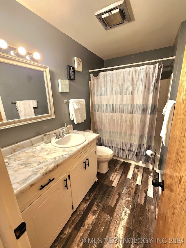 bathroom with a shower with shower curtain, wood-type flooring, vanity, and toilet