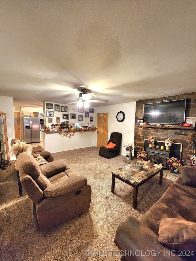 living room with ceiling fan, carpet floors, a textured ceiling, and a wood stove