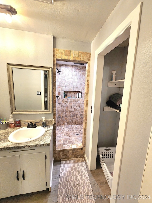 bathroom featuring hardwood / wood-style flooring, vanity, walk in shower, and a textured ceiling