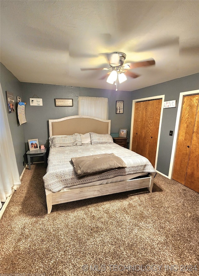 bedroom with multiple closets, ceiling fan, and dark carpet