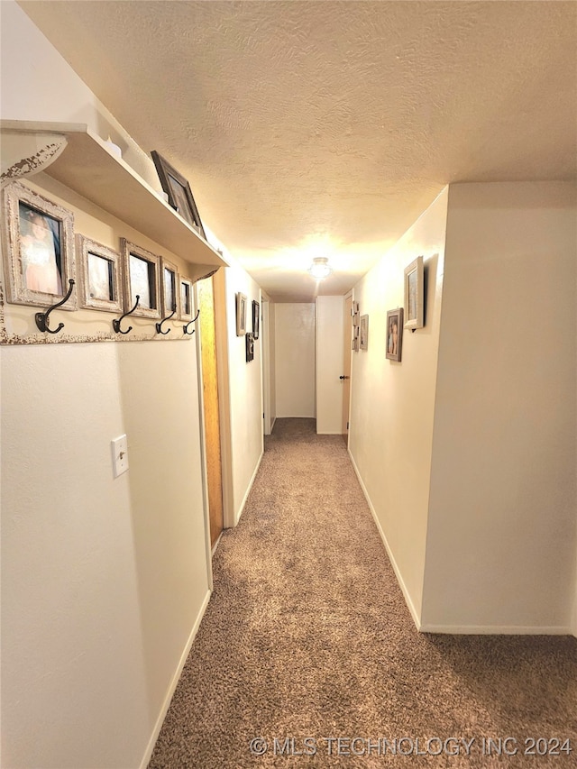 hall with carpet flooring and a textured ceiling