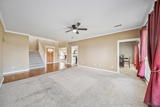 unfurnished living room featuring ornamental molding, light colored carpet, and ceiling fan