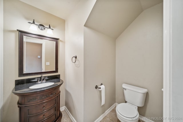 bathroom with vanity, vaulted ceiling, toilet, and tile patterned floors