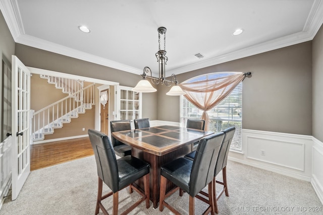 dining space featuring crown molding, a chandelier, and light wood-type flooring