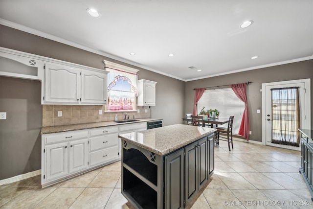 kitchen featuring decorative backsplash, a kitchen island, white cabinetry, light stone countertops, and sink