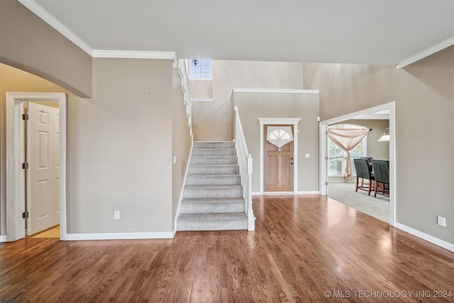 stairway with wood-type flooring and ornamental molding