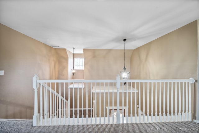 hall with carpet flooring and an inviting chandelier