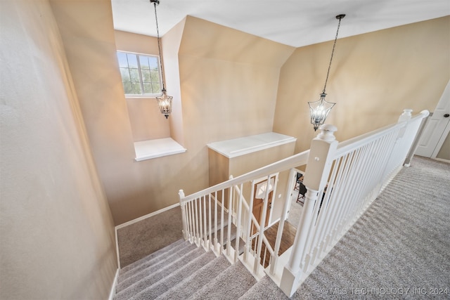 stairs featuring carpet floors, a chandelier, and vaulted ceiling