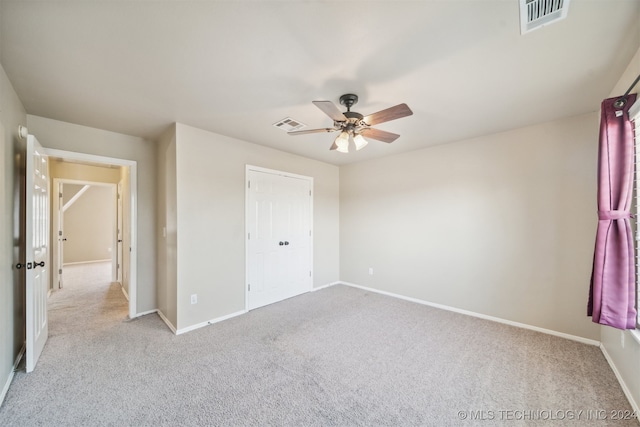 unfurnished bedroom with light colored carpet, a closet, and ceiling fan