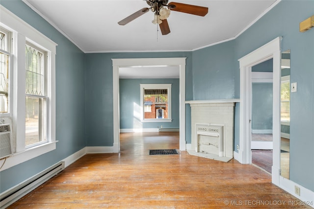 empty room featuring a wealth of natural light, a brick fireplace, light wood-type flooring, and baseboard heating