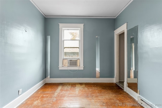 empty room with a baseboard radiator, cooling unit, ornamental molding, and light wood-type flooring