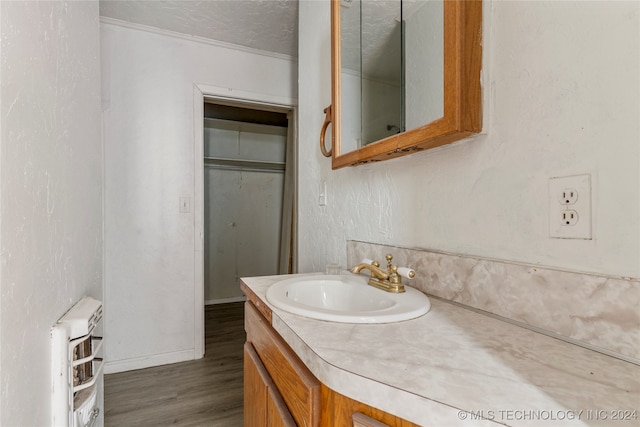 bathroom with vanity, hardwood / wood-style floors, a textured ceiling, and heating unit