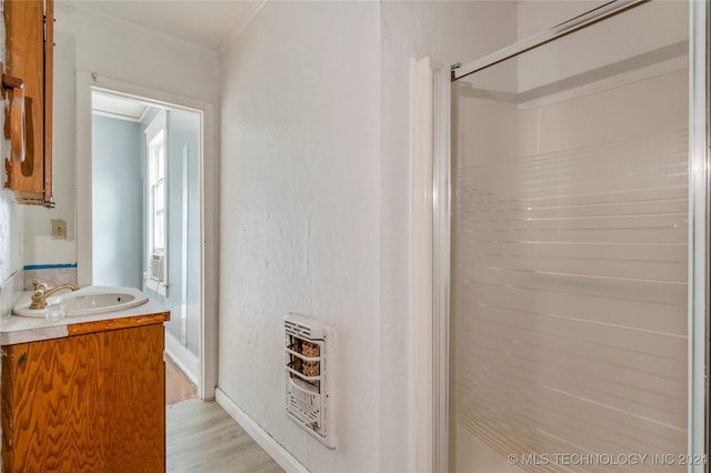 bathroom featuring heating unit, walk in shower, hardwood / wood-style flooring, vanity, and crown molding