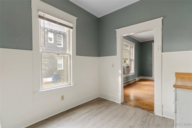 unfurnished room with baseboard heating, ornamental molding, light hardwood / wood-style floors, and plenty of natural light