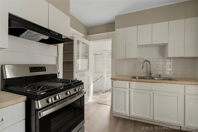 kitchen with sink, stainless steel gas range oven, white cabinetry, and light wood-type flooring