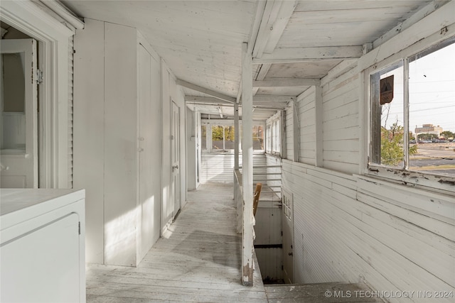 hallway featuring lofted ceiling, washer / clothes dryer, wooden walls, and plenty of natural light