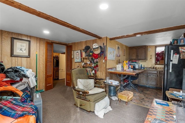 interior space featuring wood walls, beamed ceiling, and black refrigerator