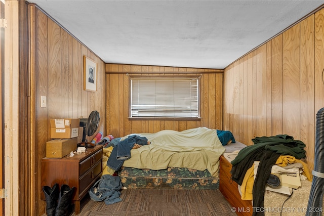 bedroom with vaulted ceiling, carpet floors, and wood walls