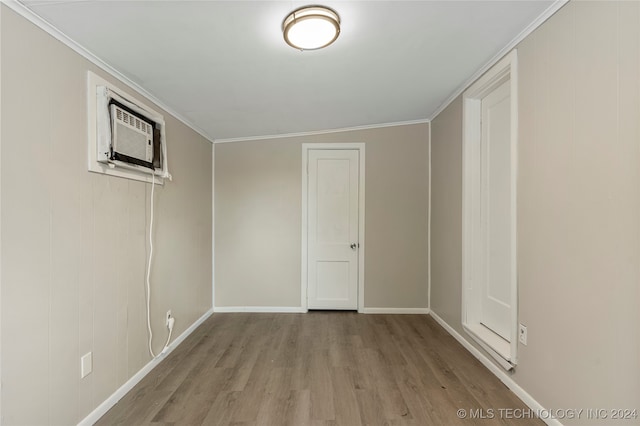 spare room featuring lofted ceiling, crown molding, a wall unit AC, and light wood-type flooring