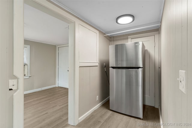 kitchen featuring wooden walls, stainless steel refrigerator, and light wood-type flooring