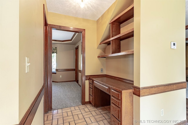 hall featuring a textured ceiling and light colored carpet