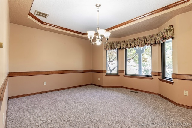 spare room featuring a notable chandelier, carpet flooring, a textured ceiling, and ornamental molding