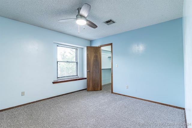 unfurnished room featuring a textured ceiling, carpet flooring, and ceiling fan