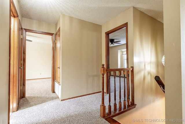 corridor with carpet flooring and a textured ceiling